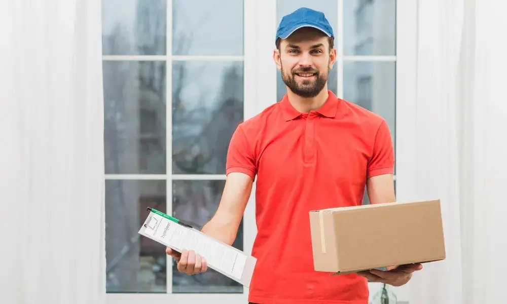 A hand holding a package of medicine in front of a home